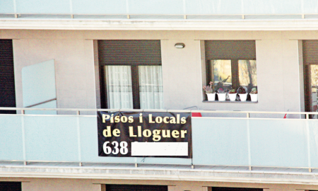 Un cartell de lloguer de pisos i locals al balcó d’un edifici