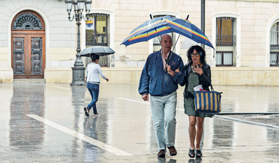 Una parella passeja sota la pluja a la Plaça de Sant Roc